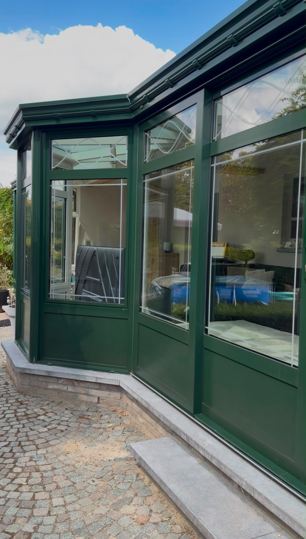 Serre met zwarte stalen kozijnen aan een bakstenen huis